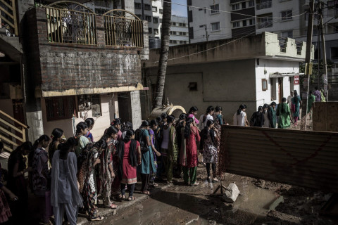 A parade of women walking from their dorms to various factories sidestepping sewage and construction. Credit: Andrea Bruce / NOOR
